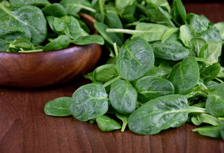 Fresh baby spinach leaves on a wooden background stock images. Fresh green spinach in a wooden bowl. Healthy leafy vegetables on the table close-up stock photoの写真素材