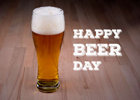 Happy Beer Day Poster stock images. Full glass of beer on the table images. Fresh lager on a wooden...
