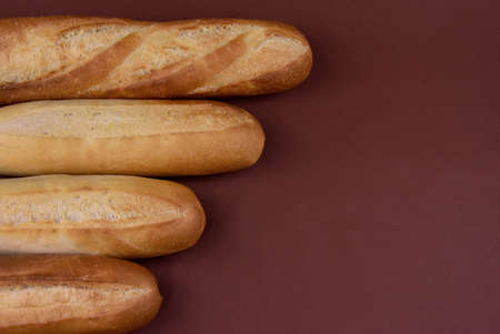 French baguettes isolated on a brown background top view stock images. Pile of french bread still life frame stock photo. Fresh baguettes on a brown background with copy space for textの写真素材