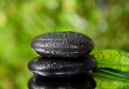 Spa massage stones on a fresh green background stock images. Spa and wellness frame stock images. Pile of black stones photo. Spa-concept with zen stones with copy space for textの写真素材