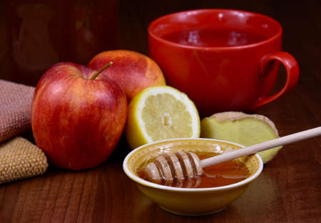 Autumn still life with honey, apples, ginger and a cup of tea stock images. Bowl of honey with a dipper, lemon, red apples and ginger on the table stock photo. Healthy food when sick imagesの写真素材