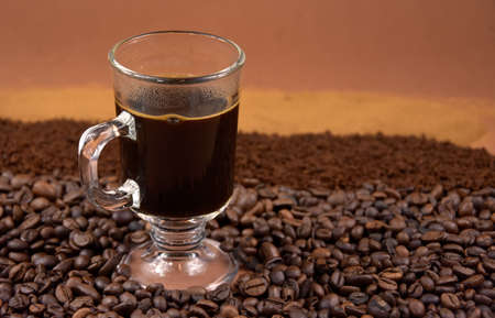 Cup of black hot coffee with roasted coffee beans stock images. Coffee in a small glass cup and pile...