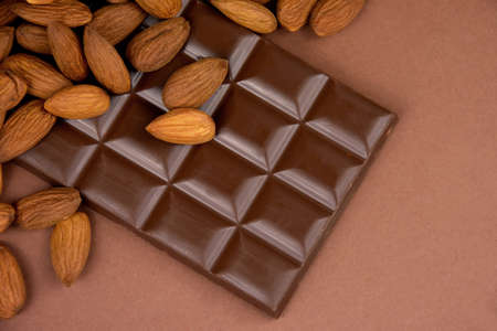 Milk chocolate bar with almonds brown frame top view stock images. Whole almond chocolate on a brown background with copy space for text stock imagesの写真素材