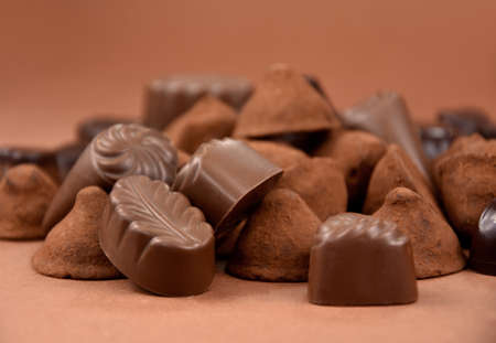 Chocolate pralines and truffles on a brown background stock images. Pile of chocolate truffles and...