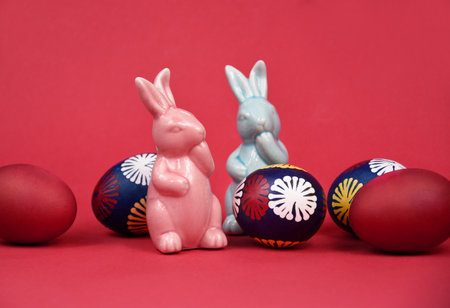 Two cute easter ceramic bunnies figurines and easter eggs stock images. Pink and blue easter bunny spring decoration still life stock photo. Easter decoration with colored eggsの写真素材