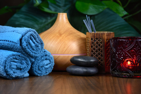 Spa still life with aromatherapy diffuser, massage stones, towels and candle on wooden background stock photo images. Spa wellness setting with wooden aroma humidifier and towelsの写真素材