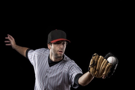 Baseball Player catching a ball on a black background. Studio Shot.