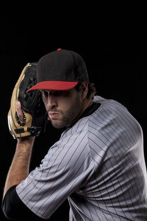 Baseball Player pitching a ball on a black background. Studio Shot.