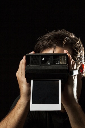 Photographer with a instant camera with a photography on black の写真素材