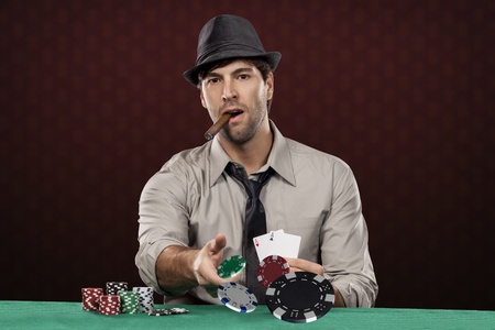 Poker player, on a red background, throwing poker chips.の写真素材