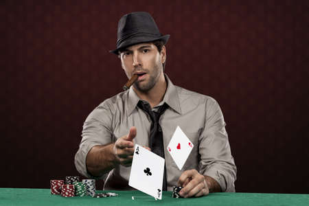 Poker player, on a red background, throwing two ace cards.の写真素材