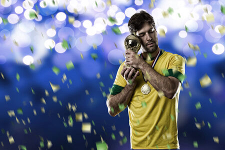 Brazilian soccer player, celebrating the championship with a trophy in his hand, on a blue background.の写真素材