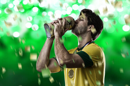 Brazilian soccer player, celebrating the championship with a trophy in his hand, on a green background.の写真素材