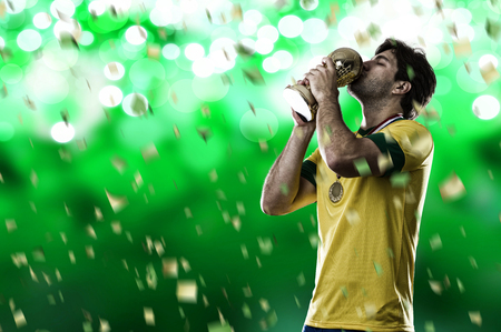 Brazilian soccer player, celebrating the championship with a trophy in his hand, on a green background.の写真素材