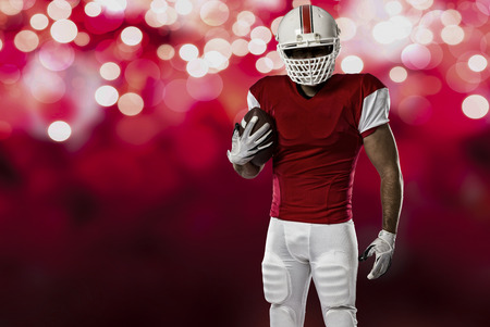 Football Player with a red uniform on a red lights background.の写真素材