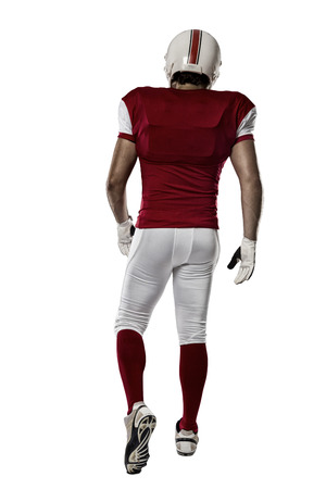 Football Player with a red uniform walking, showing his back on a white background.の写真素材