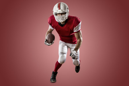 Football Player with a red uniform Running on a red background.の写真素材
