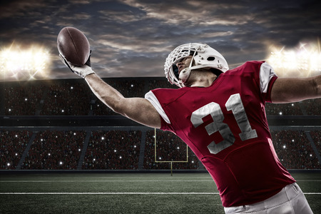 Football Player with a red uniform catching a ball on a stadium..