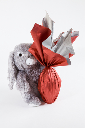 A plush rabbit holding a brazilian Easters egg, on a white background.の写真素材