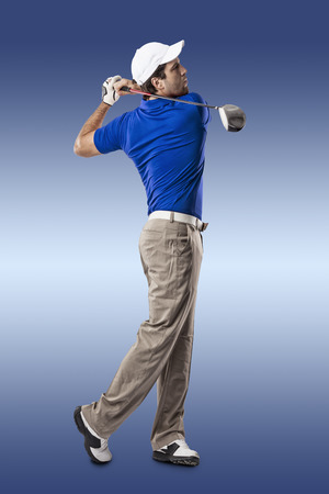 Golf Player in a blue shirt taking a swing, on a blue Background.の写真素材