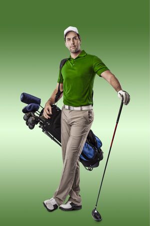 Golf Player in a green shirt, standing with a bag of golf clubs on his back, on a green Background.の写真素材