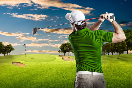 Golf Player in a green shirt taking a swing, on a golf course.の写真素材