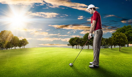 Golf Player in a red shirt taking a swing, on a golf course.の写真素材