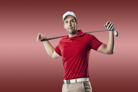 Golf Player in a red shirt taking a swing, on a red Background.の写真素材