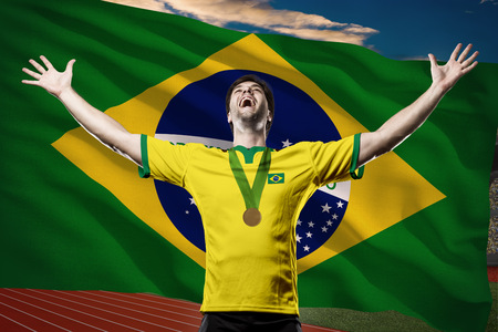 Brazilian Athlete Winning a golden medal in front of a brazilian flag.の写真素材