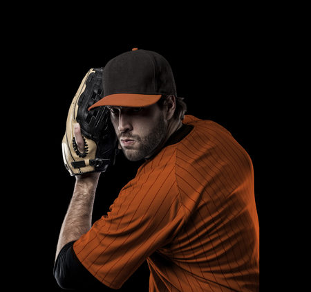 Pitcher Baseball Player with a orange uniform on a black background.の写真素材