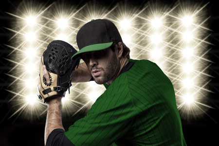 Baseball Player with a green uniform in front of lights.の写真素材