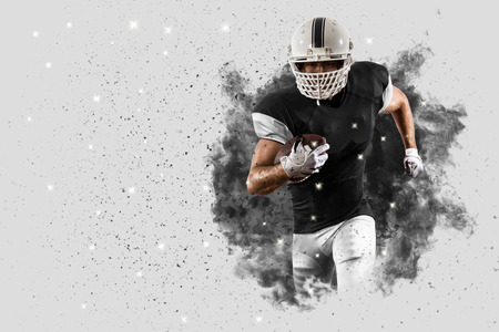 Football Player with a black uniform coming out of a blast of smoke .の写真素材