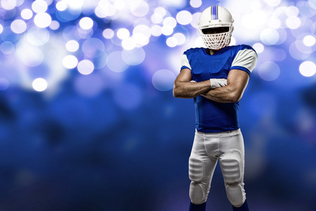Football Player with a blue uniform on a blue lights background.の写真素材