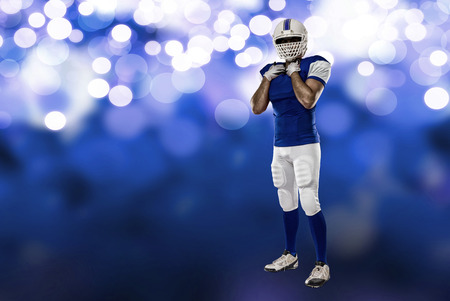 Football Player with a blue uniform on a blue lights background.の写真素材