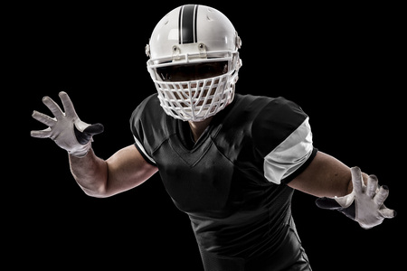 Football Player with a black uniform making a tackle on a black background.の写真素材