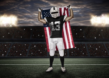 Football Player with a Black uniform and a american flag, on a stadium.の写真素材