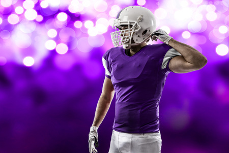 Football Player with a purple uniform on a purple lights background.の写真素材