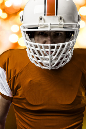 Close up of a Football Player with a orange uniform on a orange lights background.の写真素材