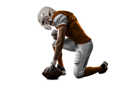 Football Player with a orange uniform on his knees, on a white background.の写真素材