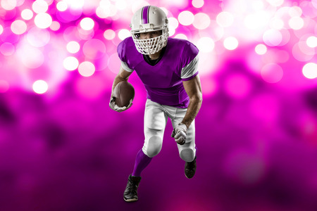 Football Player with a pink uniform Running on a pink lights background.の写真素材