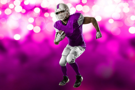 Football Player with a pink uniform Running on a pink lights background.の写真素材