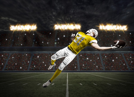 Football Player with a yellow uniform catching a ball on a stadium.の写真素材