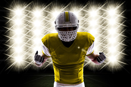 Football Player with a yellow uniform in front of lights.の写真素材