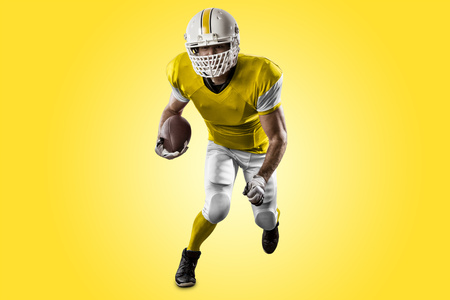 Football Player with a yellow uniform Running on a yellow background.の写真素材