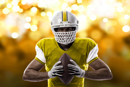 Football Player with a yellow uniform on a yellow lights background.の写真素材