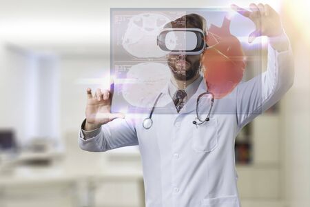 Male doctor in his office,using a Virtual Reality Glasses, looking at a virtual heart.の写真素材