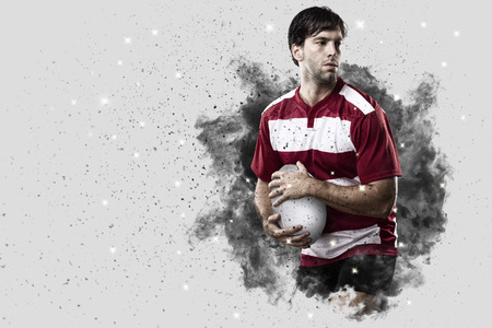 Rugby Player with a red uniform coming out of a blast of smoke .の写真素材
