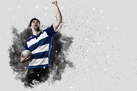 Rugby Player with a blue uniform coming out of a blast of smoke .の写真素材