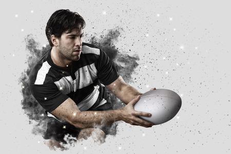 Rugby Player with a black uniform coming out of a blast of smoke .の写真素材