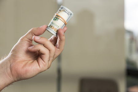 Roll of 100 dollar bills in a man's handの写真素材